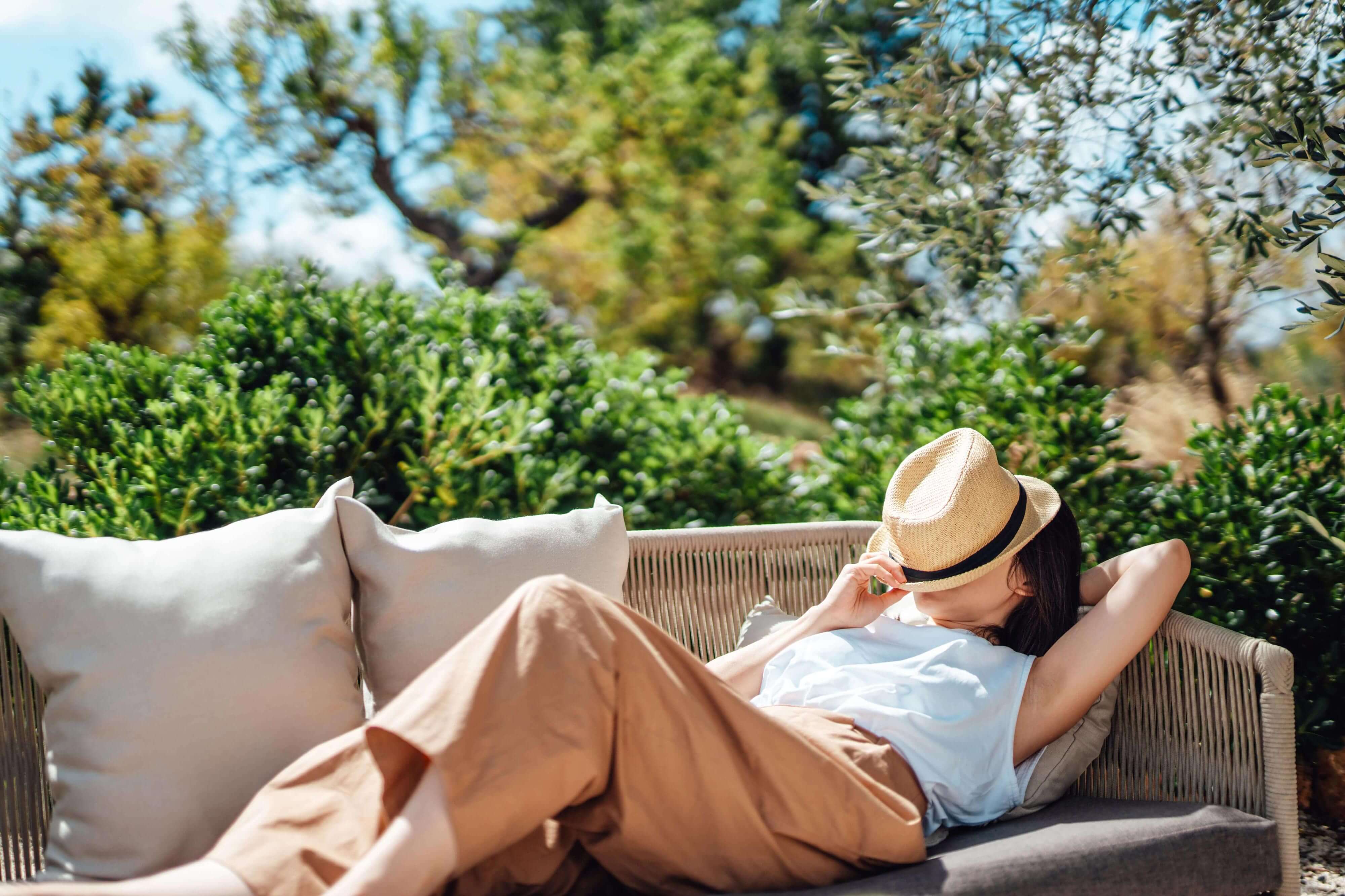 Young woman asleep on an outdoor chair with a hat covering her face
