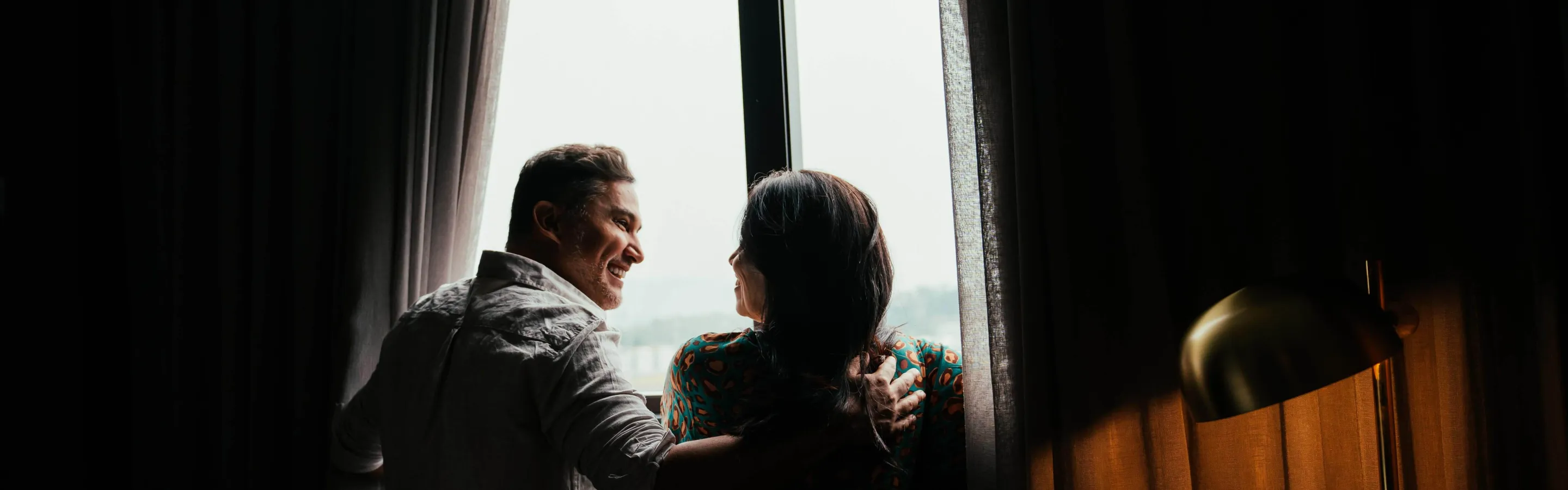 Man and woman looking out of a window in a hotel room