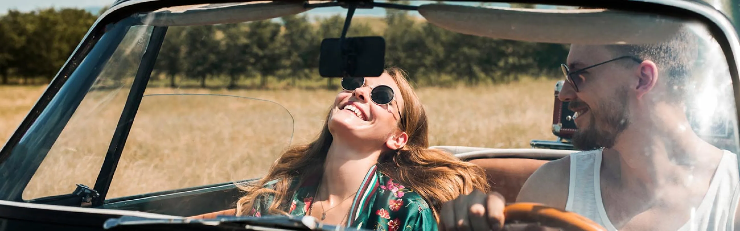 Young couple driving in a convertible car on a sunny day