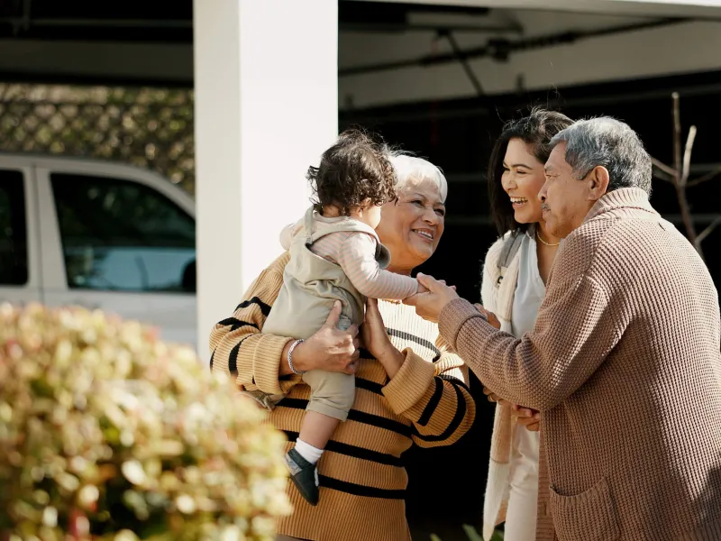 Family hugging small baby in front of home