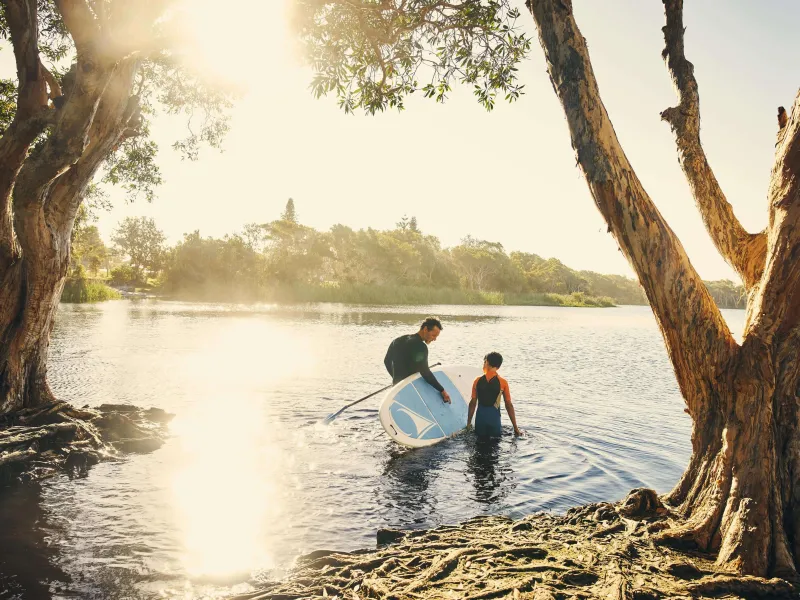 Father and young sun paddle boarding on a lake