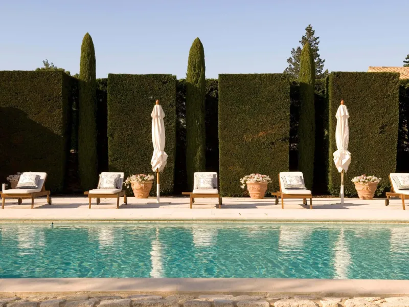 Five deck chairs and umbrellas lined up next to a pool