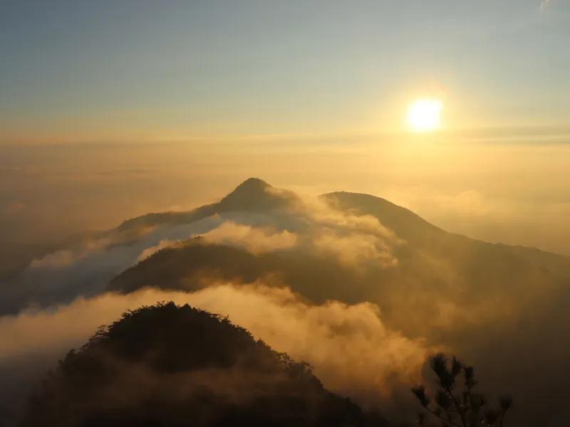 Sun shining above the clouds on top of a mountain
