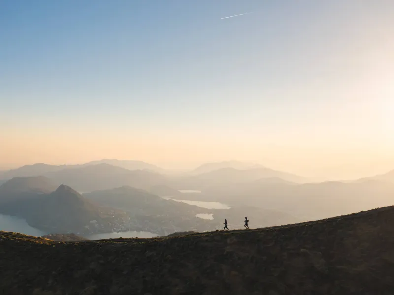 Two trail runners scaling a mountain