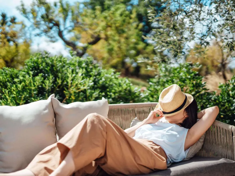 Young woman asleep on an outdoor chair with a hat covering her face