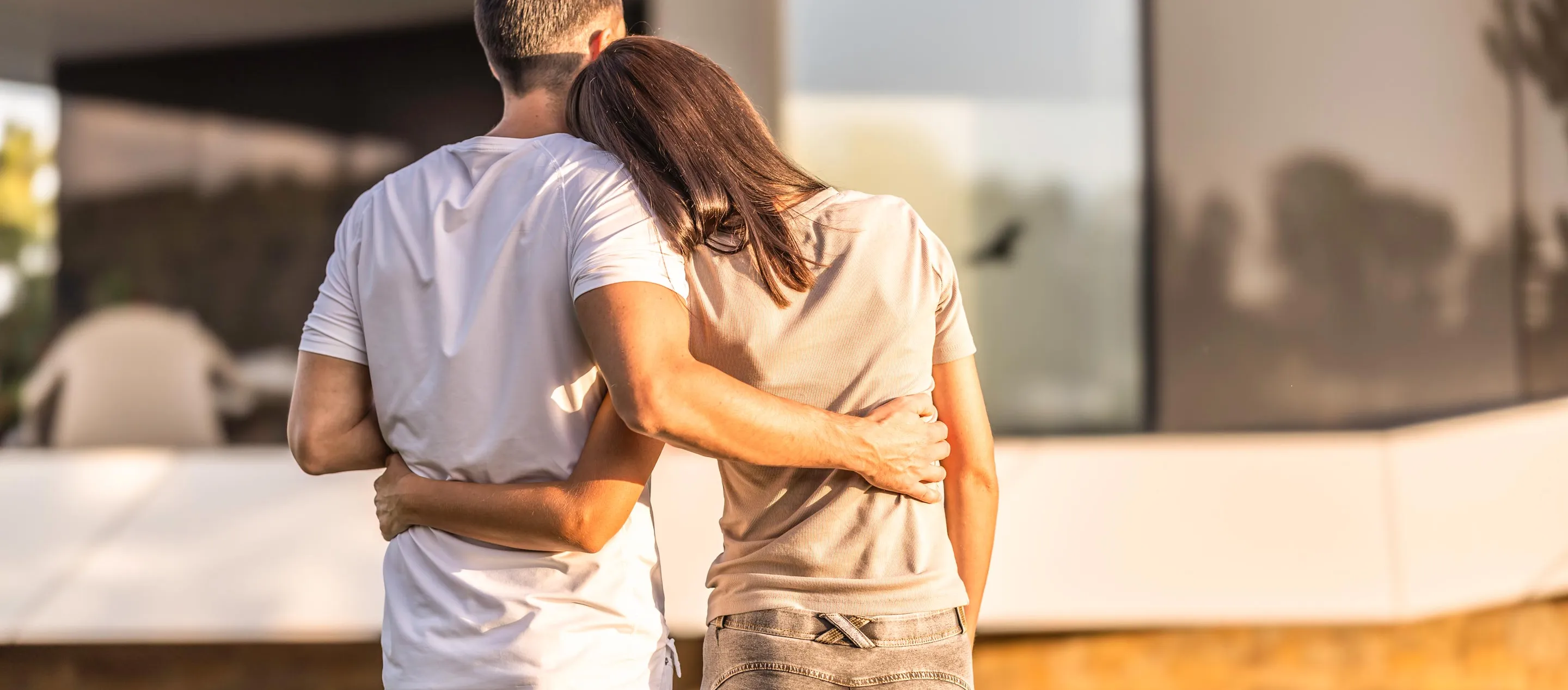 Couple facing away from the camera hugging in front of home