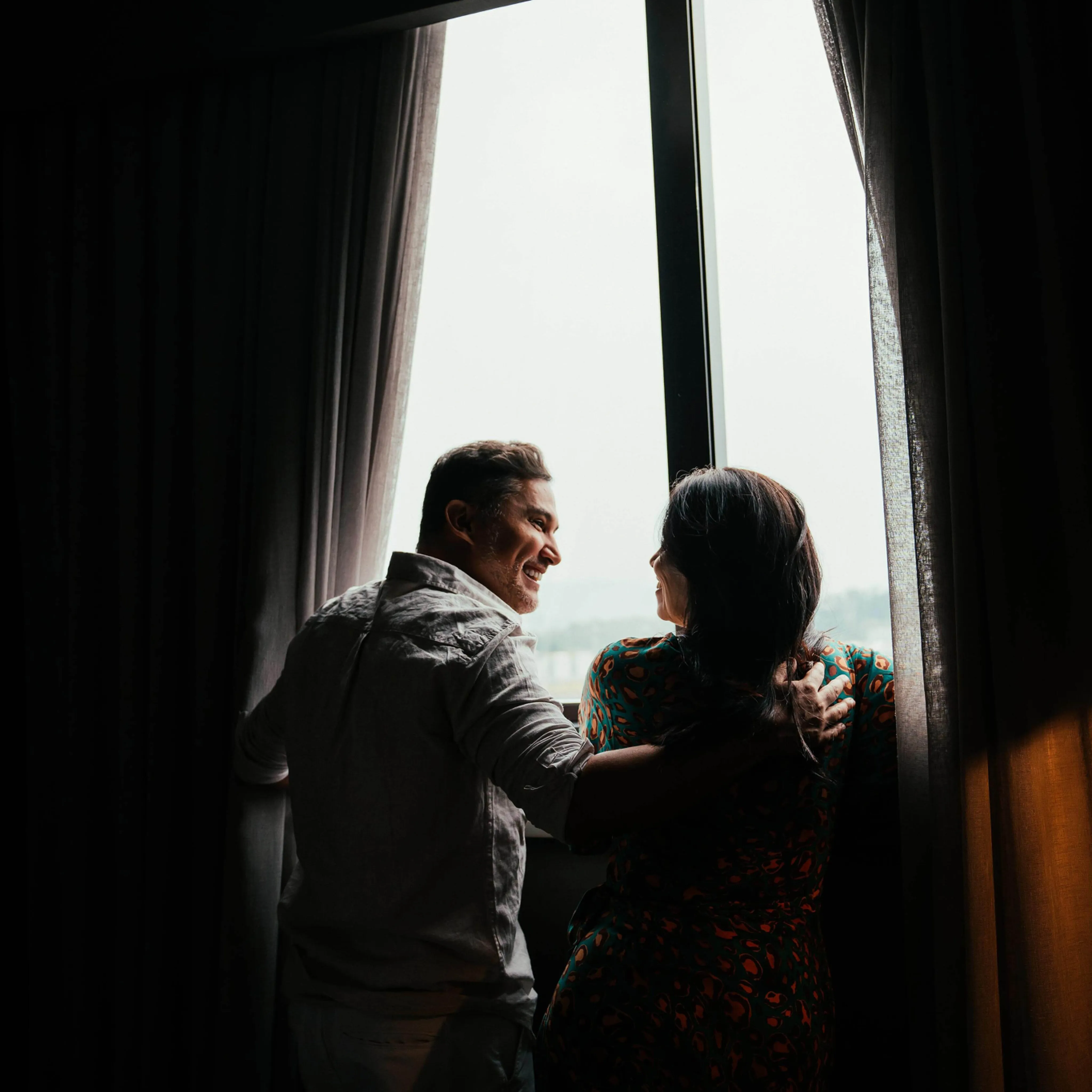 Man and woman looking out of a window in a hotel room