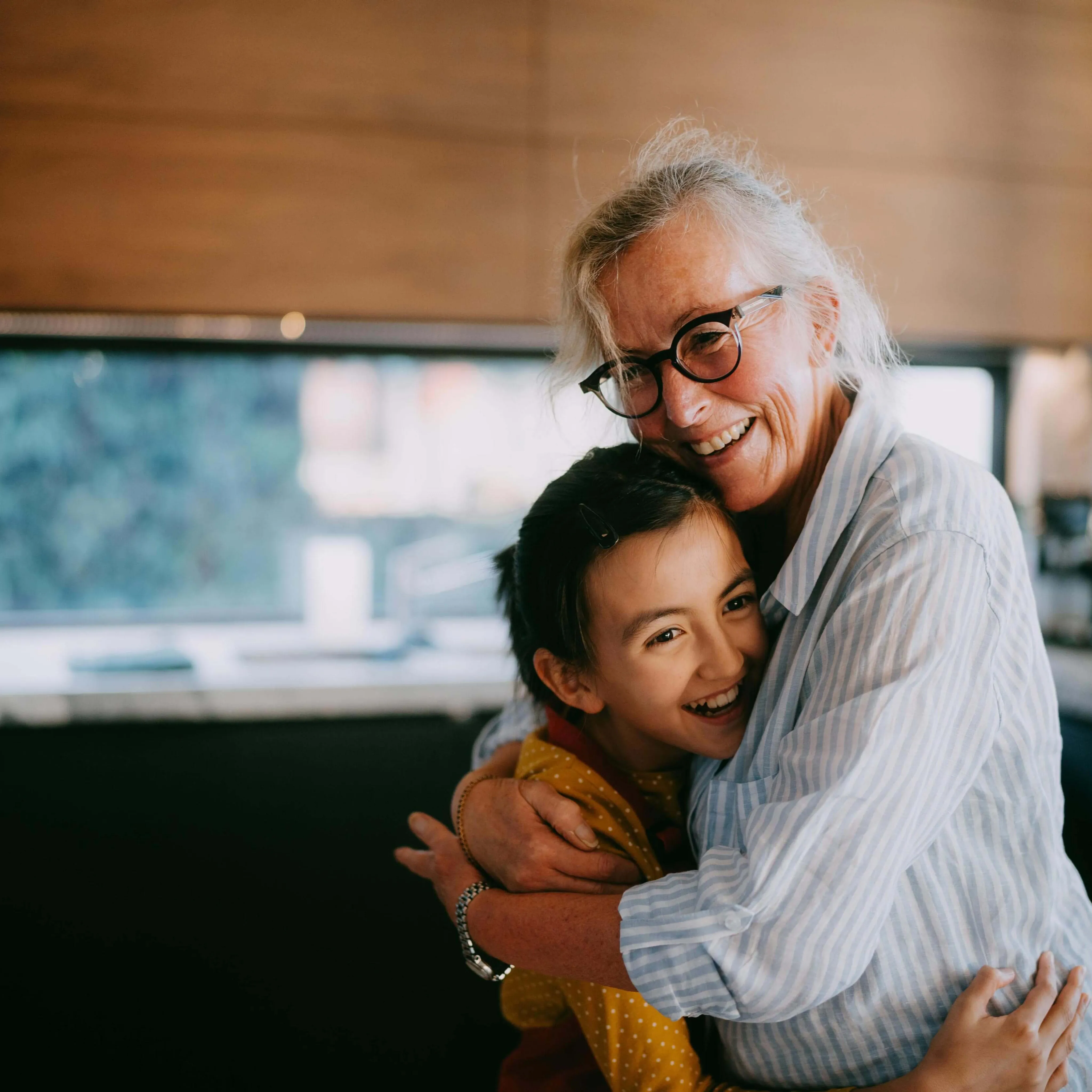 Grandmother and young child hugging and smiling in the kitchen