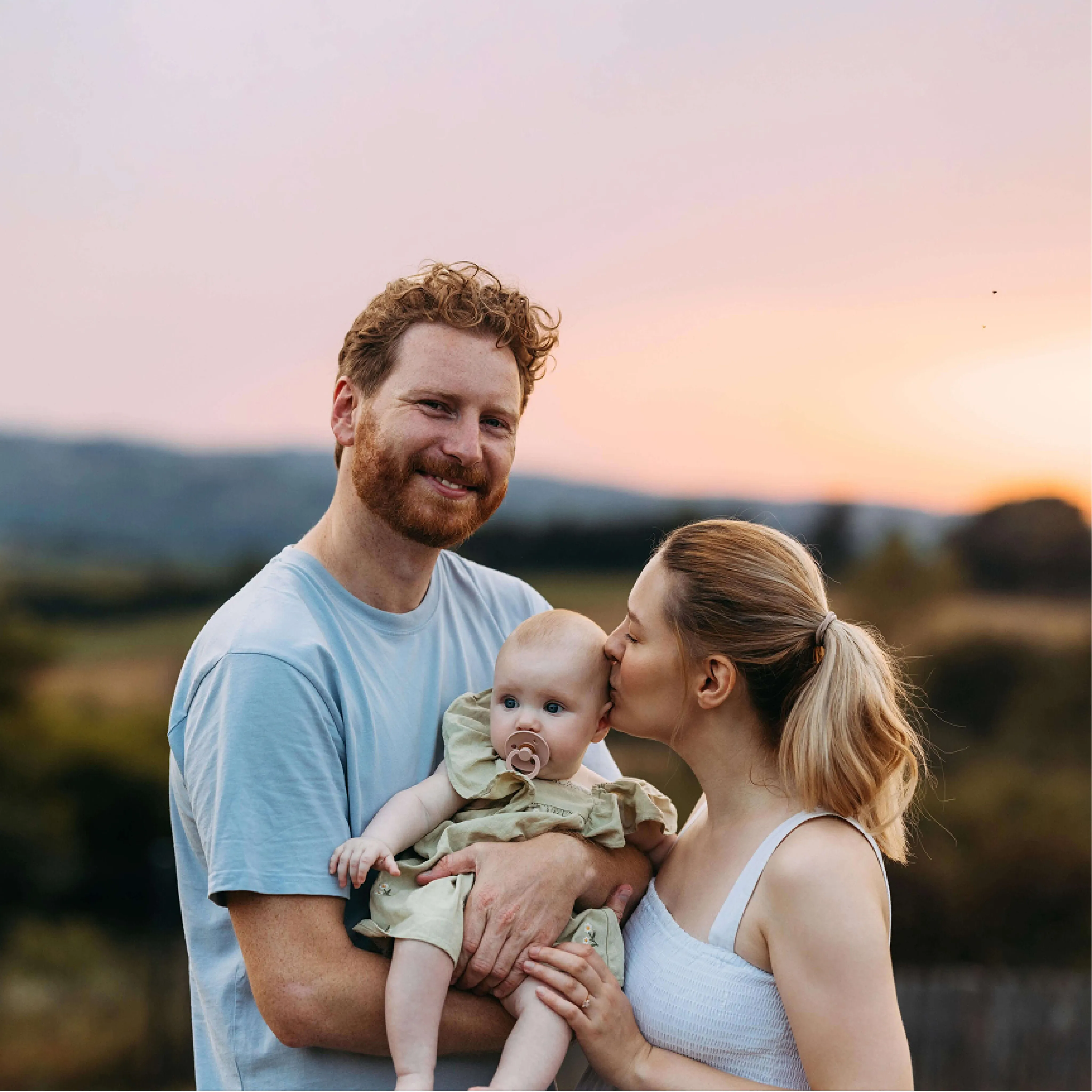 Young man and woman smiling and kissing new baby
