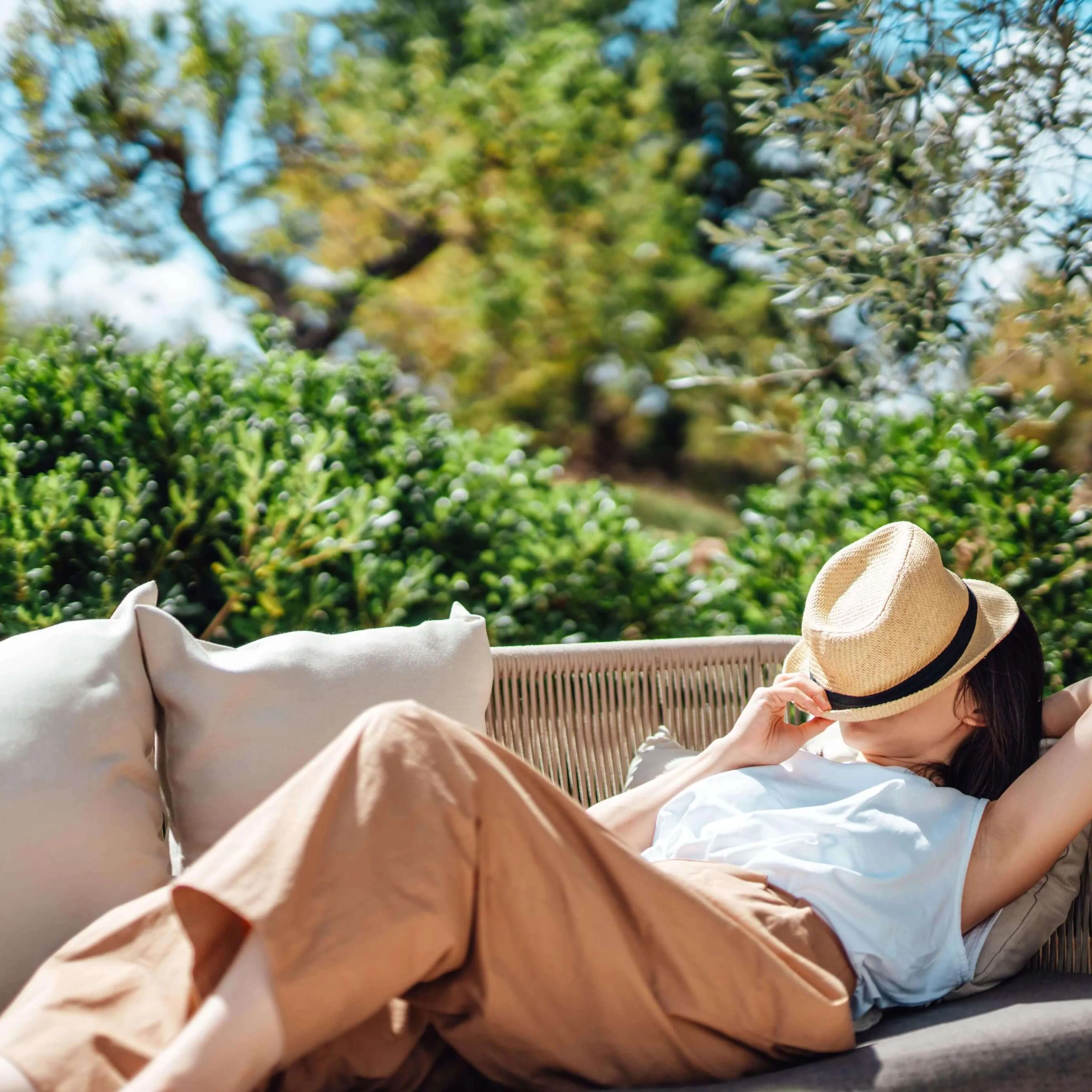 Young woman asleep on an outdoor chair with a hat covering her face