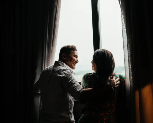 Man and woman looking out of a window in a hotel room