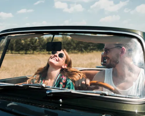Young couple driving in a convertible car on a sunny day